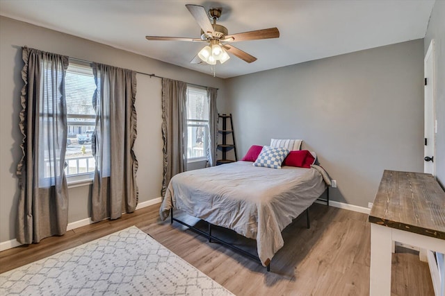 bedroom with ceiling fan, wood finished floors, and baseboards