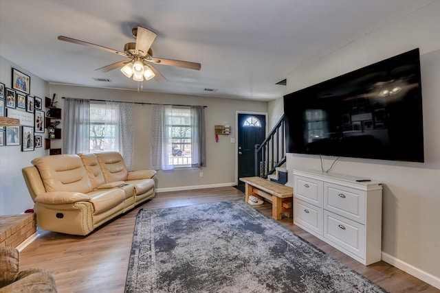 living room with visible vents, stairway, baseboards, and wood finished floors