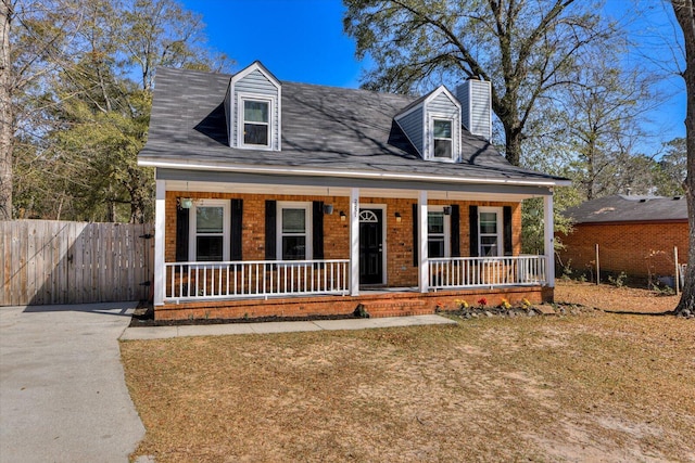 cape cod-style house with a porch, brick siding, fence, and a chimney