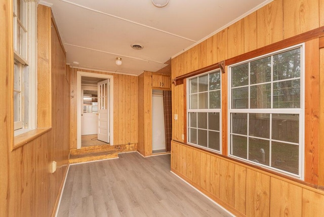 interior space featuring light hardwood / wood-style floors, ornamental molding, and wood walls