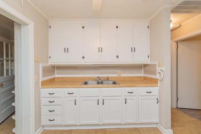 kitchen with sink, white cabinets, and ornamental molding