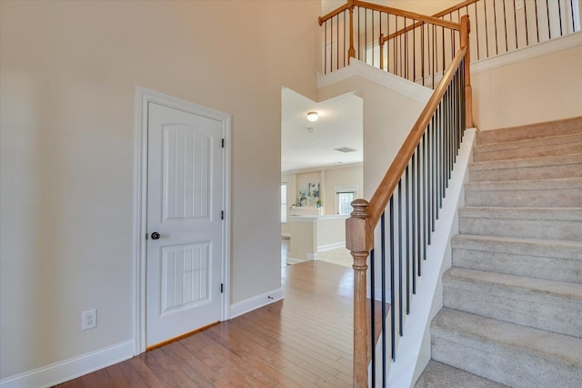 stairs with a high ceiling and wood-type flooring