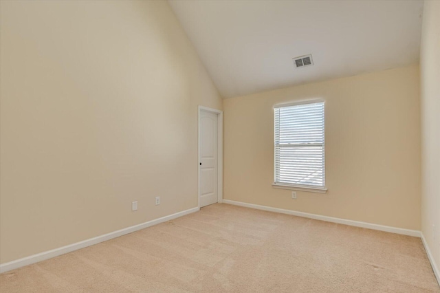 empty room with high vaulted ceiling and light colored carpet