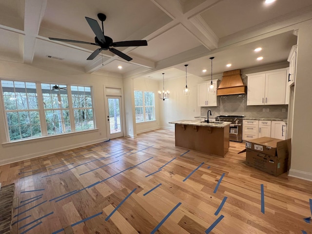 kitchen with white cabinetry, custom range hood, a kitchen island with sink, and coffered ceiling