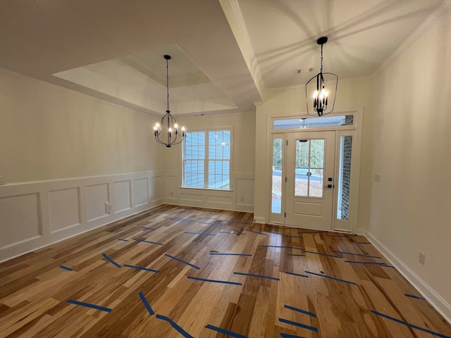 entrance foyer with a tray ceiling, crown molding, a chandelier, and hardwood / wood-style flooring