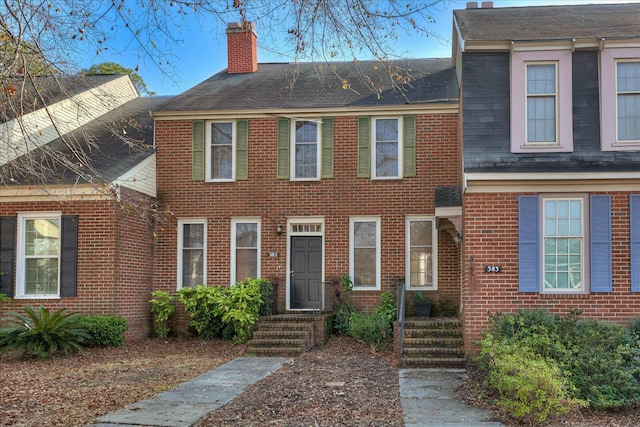 view of front of property featuring a chimney and brick siding