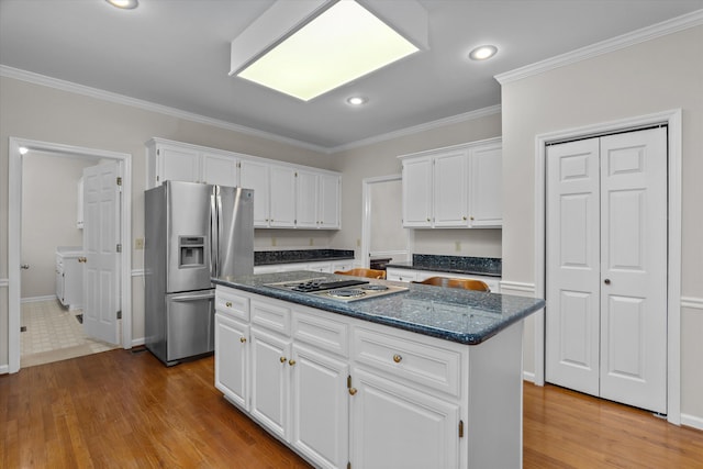 kitchen featuring appliances with stainless steel finishes, white cabinets, a center island, crown molding, and light wood-type flooring