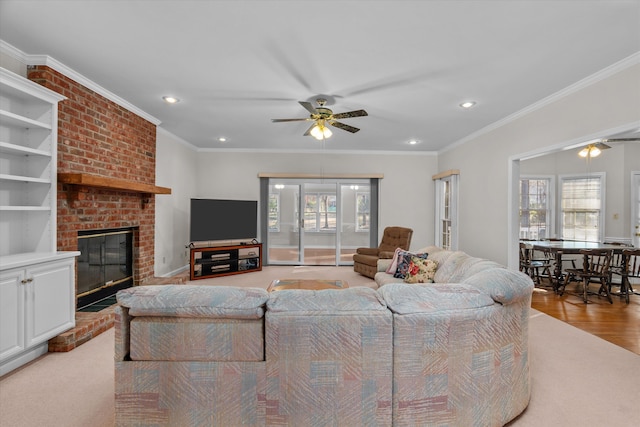 living room featuring a brick fireplace, plenty of natural light, ornamental molding, and ceiling fan