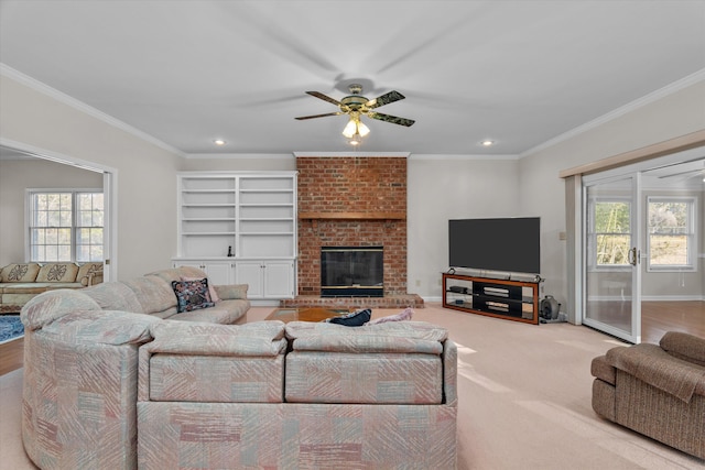 carpeted living room featuring a brick fireplace, built in shelves, ornamental molding, and ceiling fan