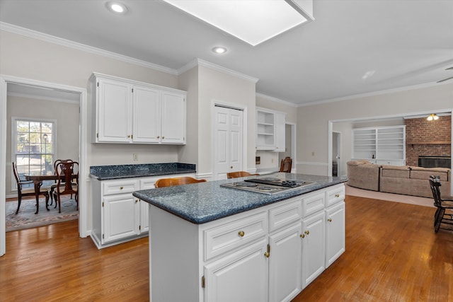 kitchen with white cabinetry, light hardwood / wood-style floors, stainless steel gas stovetop, and a kitchen island