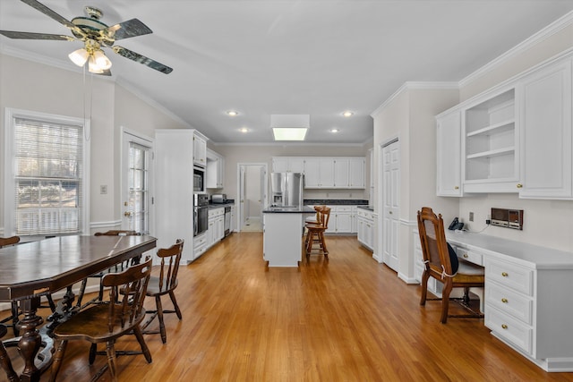 dining space with ceiling fan, ornamental molding, built in desk, and light wood-type flooring