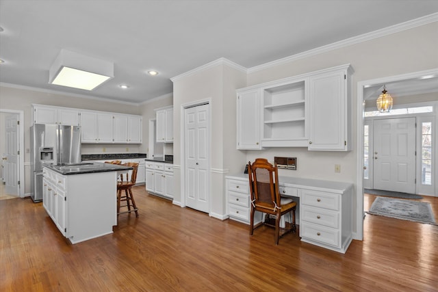 kitchen with white cabinetry, a kitchen bar, stainless steel fridge with ice dispenser, and a kitchen island