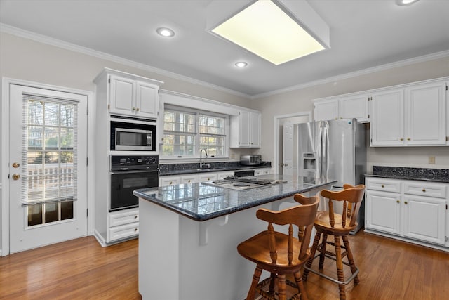 kitchen featuring stainless steel appliances, a kitchen island, sink, and white cabinets