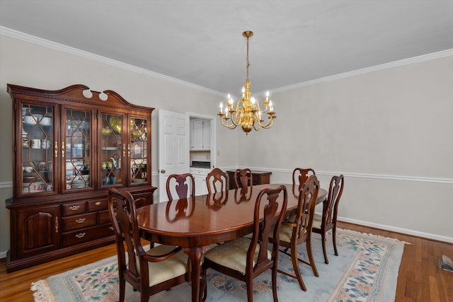 dining room featuring crown molding, an inviting chandelier, and light hardwood / wood-style floors