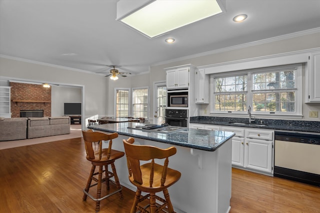 kitchen with stainless steel appliances, white cabinetry, sink, and a breakfast bar