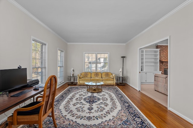 office with ornamental molding, a healthy amount of sunlight, and light hardwood / wood-style flooring