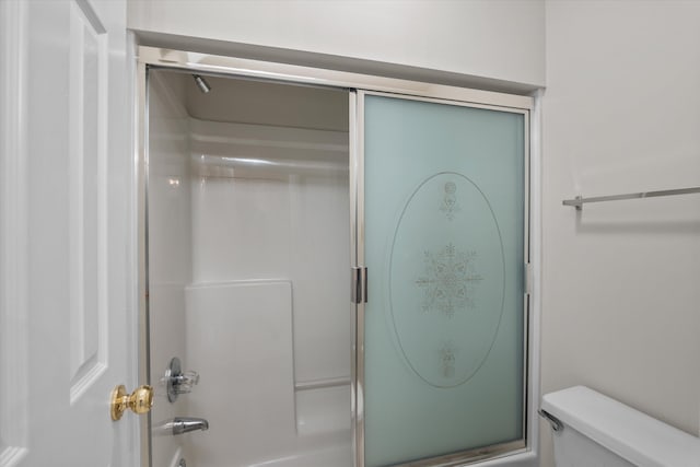 bathroom featuring combined bath / shower with glass door and toilet