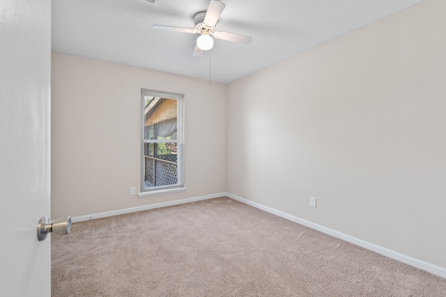 carpeted spare room featuring baseboards and ceiling fan