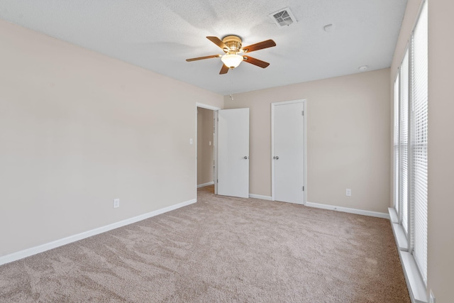 unfurnished bedroom with baseboards, a ceiling fan, visible vents, and carpet flooring