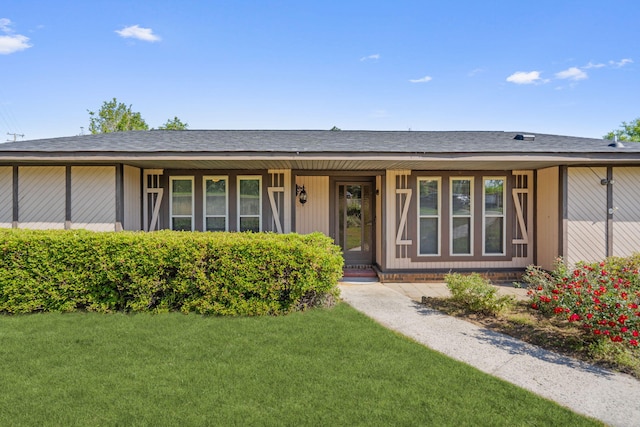 ranch-style house with roof with shingles, a porch, and a front yard