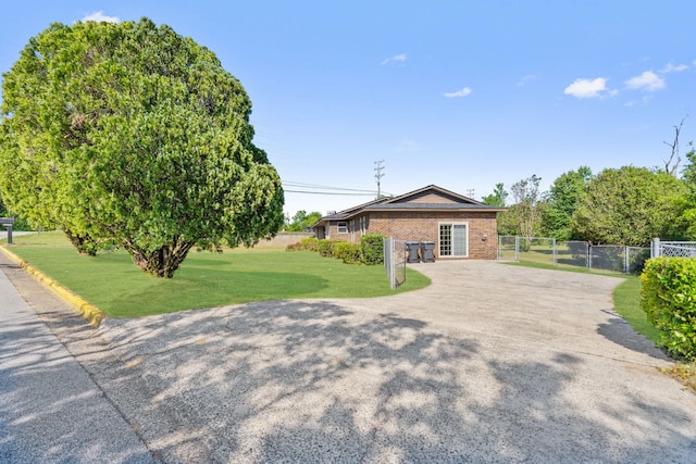 view of front facade with a gate, a front lawn, driveway, fence, and brick siding