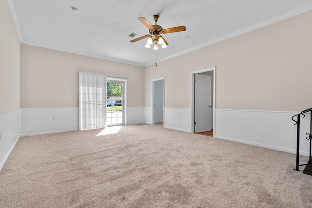 interior space with ceiling fan, visible vents, a wainscoted wall, and ornamental molding