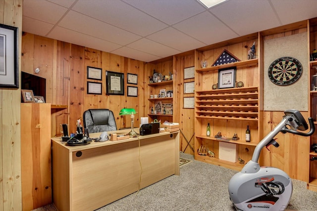 home office with a paneled ceiling, carpet floors, and wooden walls