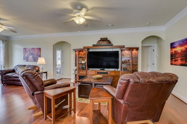 living room with crown molding, ceiling fan, and light wood-type flooring