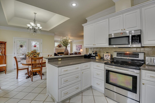 kitchen with a tray ceiling, kitchen peninsula, white cabinets, and appliances with stainless steel finishes