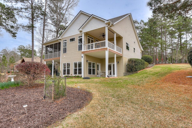 rear view of property with a yard, a sunroom, ceiling fan, and a balcony