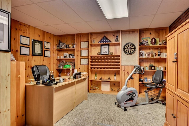 office space with a paneled ceiling, carpet floors, and wooden walls