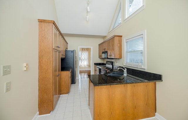 3701 Wexford Dr, Martinez, GA 30907 - kitchen with electric range, a peninsula, dark stone counters, light tile patterned floors, and brown cabinets