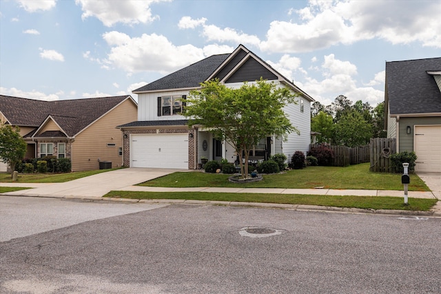 craftsman-style home featuring a front yard, fence, brick siding, an attached garage, and driveway
