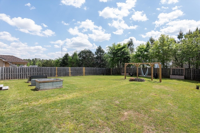 view of yard with a garden, a fenced backyard, and a fire pit