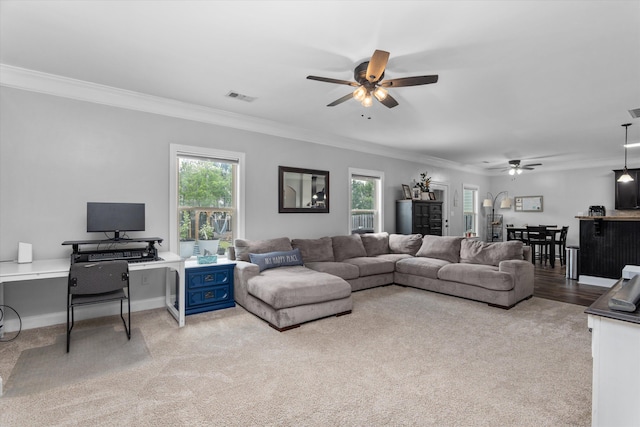 living area with visible vents, ornamental molding, and ceiling fan