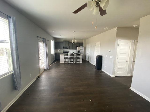 interior space featuring ceiling fan, baseboards, and dark wood-type flooring