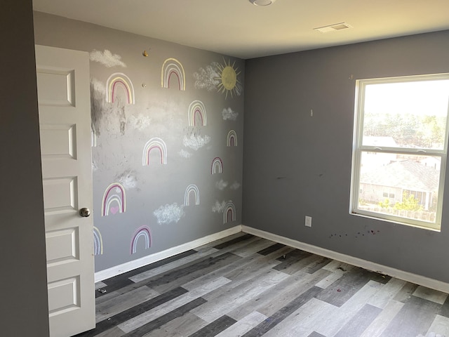 spare room with visible vents, baseboards, and wood finished floors