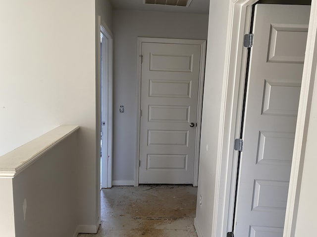 hallway featuring concrete floors and baseboards