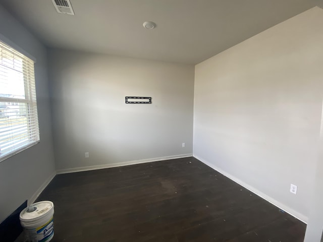 spare room featuring dark wood-style floors, baseboards, and visible vents