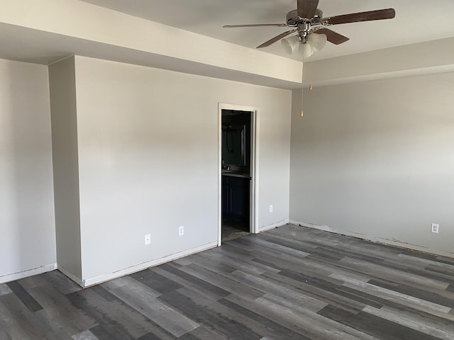 empty room featuring baseboards, a ceiling fan, and dark wood-type flooring