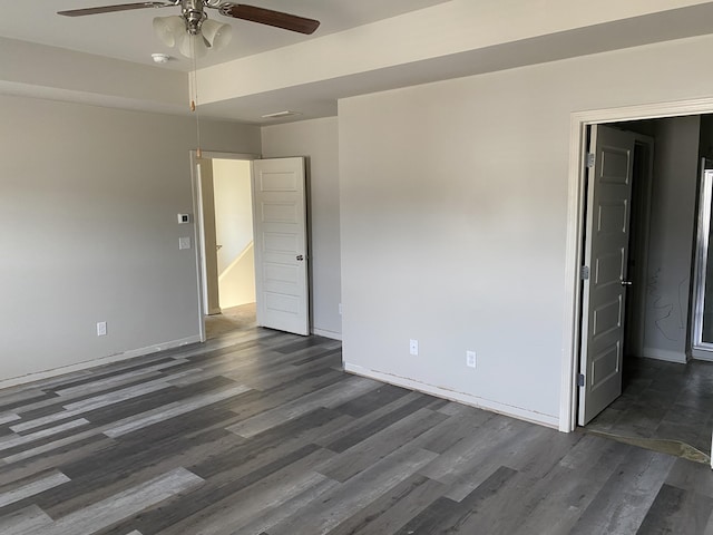 spare room featuring dark wood-type flooring, ceiling fan, and baseboards