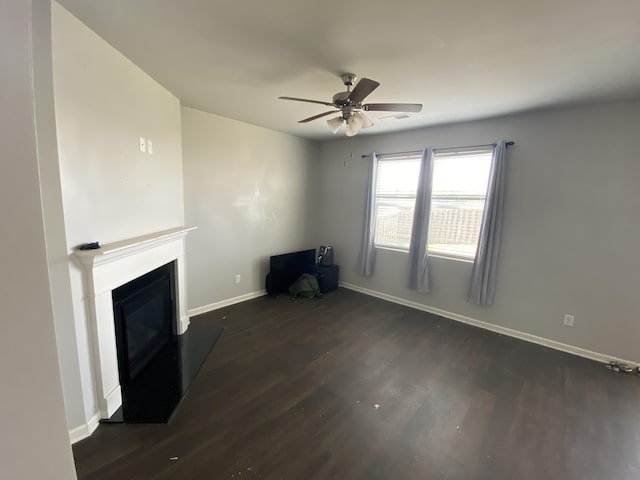 unfurnished living room with ceiling fan, wood finished floors, visible vents, baseboards, and a glass covered fireplace