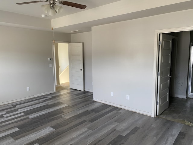 empty room featuring a ceiling fan, dark wood finished floors, and baseboards