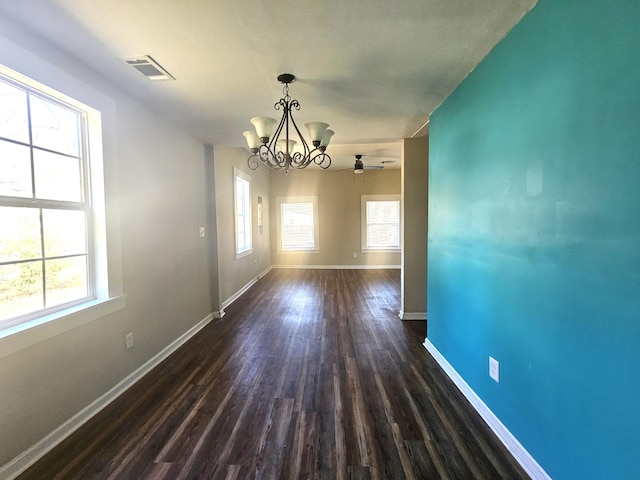 unfurnished dining area with an inviting chandelier, a healthy amount of sunlight, and dark hardwood / wood-style floors