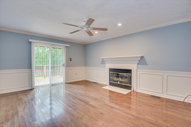 786 Springbrook Ln, Evans, GA 30809 - unfurnished living room featuring ceiling fan, a fireplace with flush hearth, wood finished floors, crown molding, and a wainscoted wall