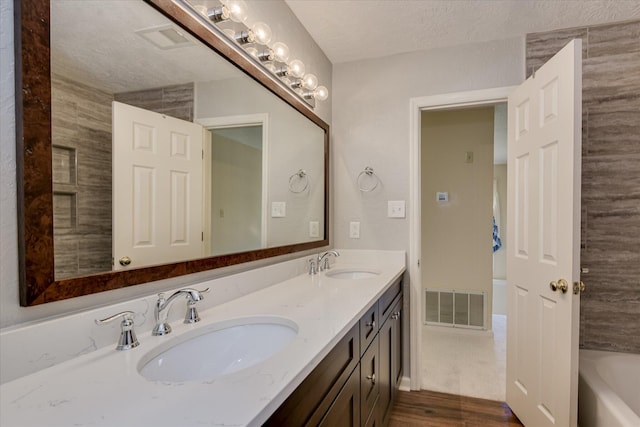 786 Springbrook Ln, Evans, GA 30809 - full bathroom with double vanity, a tub to relax in, a textured ceiling, and wood finished floors