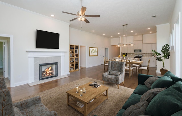 living room featuring wood finished floors, visible vents, recessed lighting, ornamental molding, and a tiled fireplace