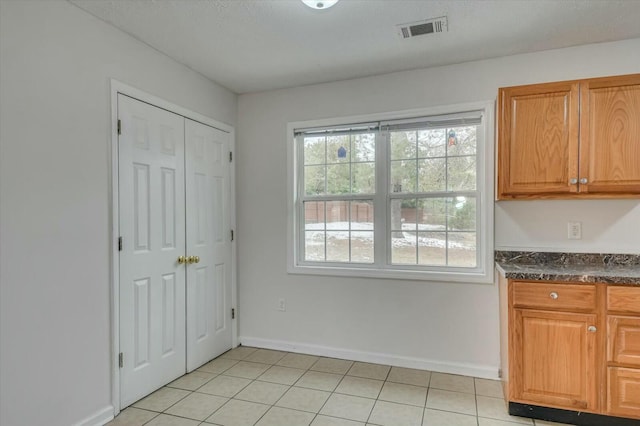 kitchen with dark stone countertops and light tile patterned floors