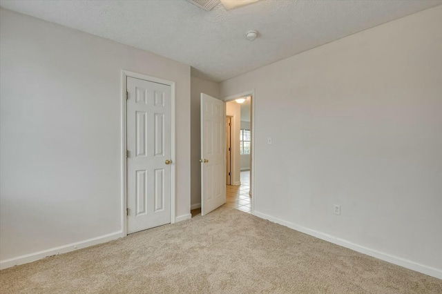 unfurnished bedroom featuring light carpet and a textured ceiling