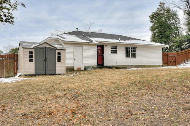 back of house with a storage shed and a lawn